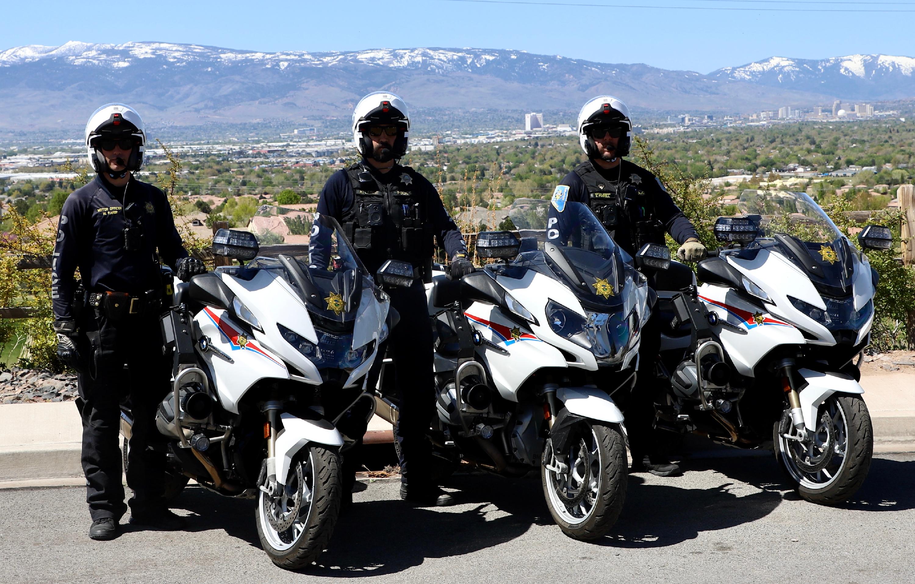 Four police officers stand beside four motorcycles